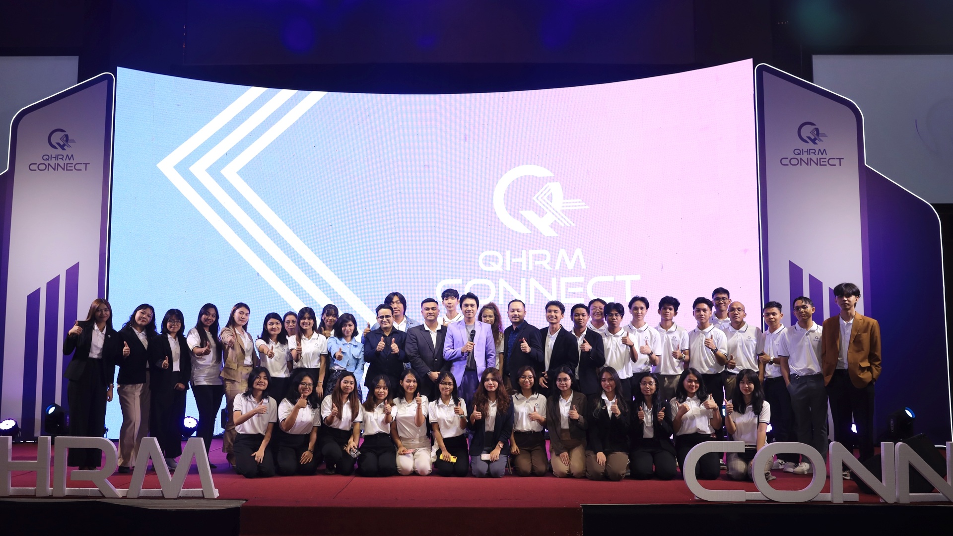 The QHRM team on stage in front of the QHRM Connect screen at the annual event